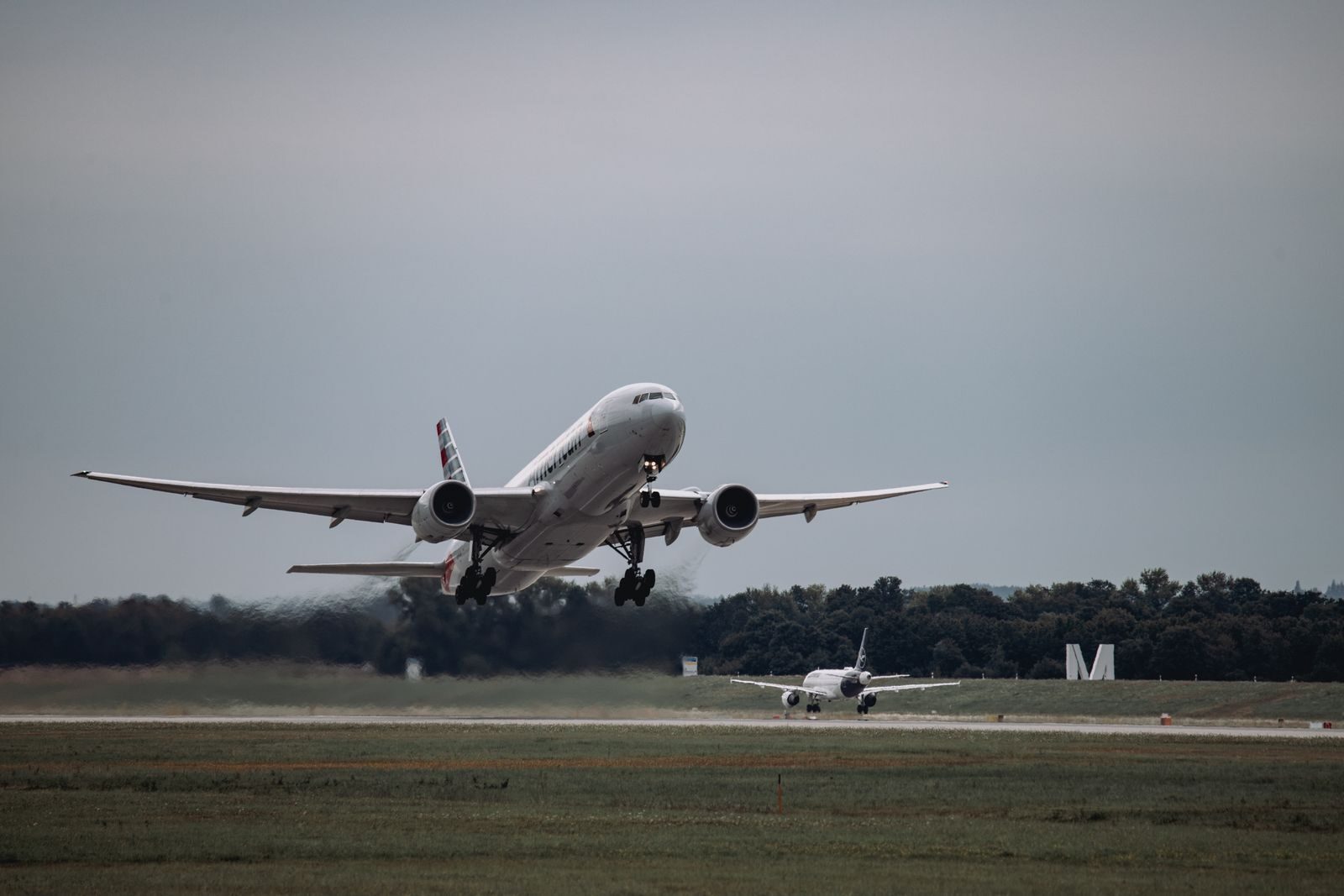 A commercial airplane taking off from Munich Airport on a cloudy day, showcasing aviation dynamics.